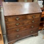 An oak drop leaf bureau with fitted interior over two short and three long drawer base,