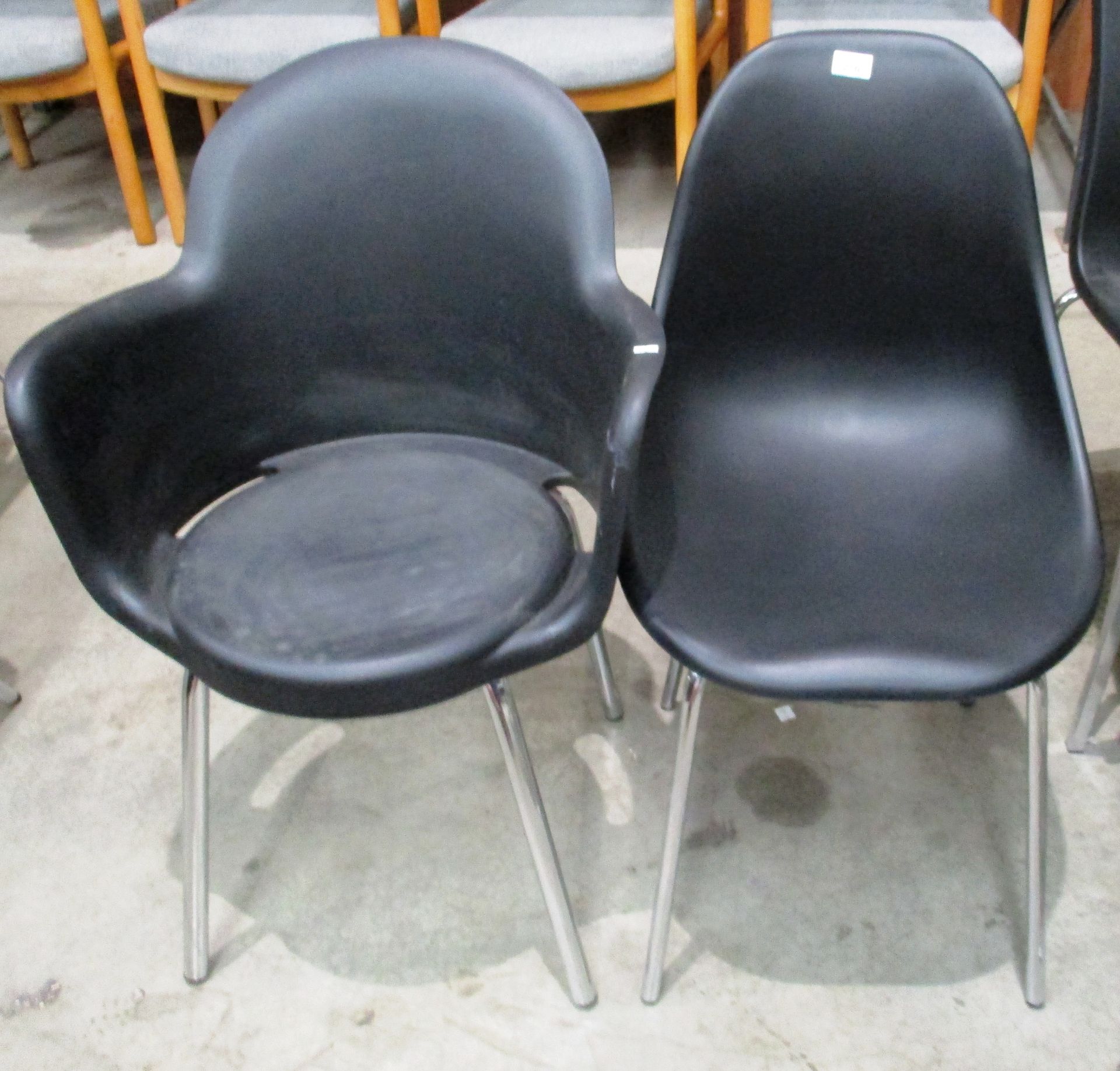 A black polypropylene shell chair on chrome legs and a black polypropylene tub armchair on chrome