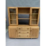 An Ercol blonde elm wall unit with two upper glazed doors with centre two shelves over two door