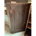 A carved oak single door wall hanging corner cabinet,