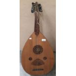 A light wood cased lute plucked string instrument with decorative carving Further