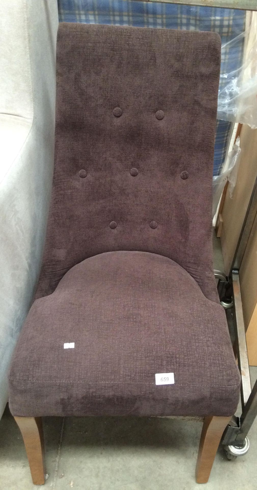 A brown upholstered button backed dining chair on dark wood feet