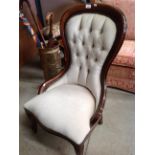 A mahogany finish framed nursing chair with beige upholstery and deep buttoned back [Please note -