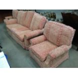 A pink and red floral patterned three piece suite comprising three seater settee and two armchairs