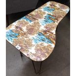 An Italian shaped retro coffee table with lake and tree patterned formica top 72cm long