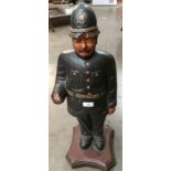 A wooden statue of English police officer 65cm high standing on a wooden plinth (damaged to right