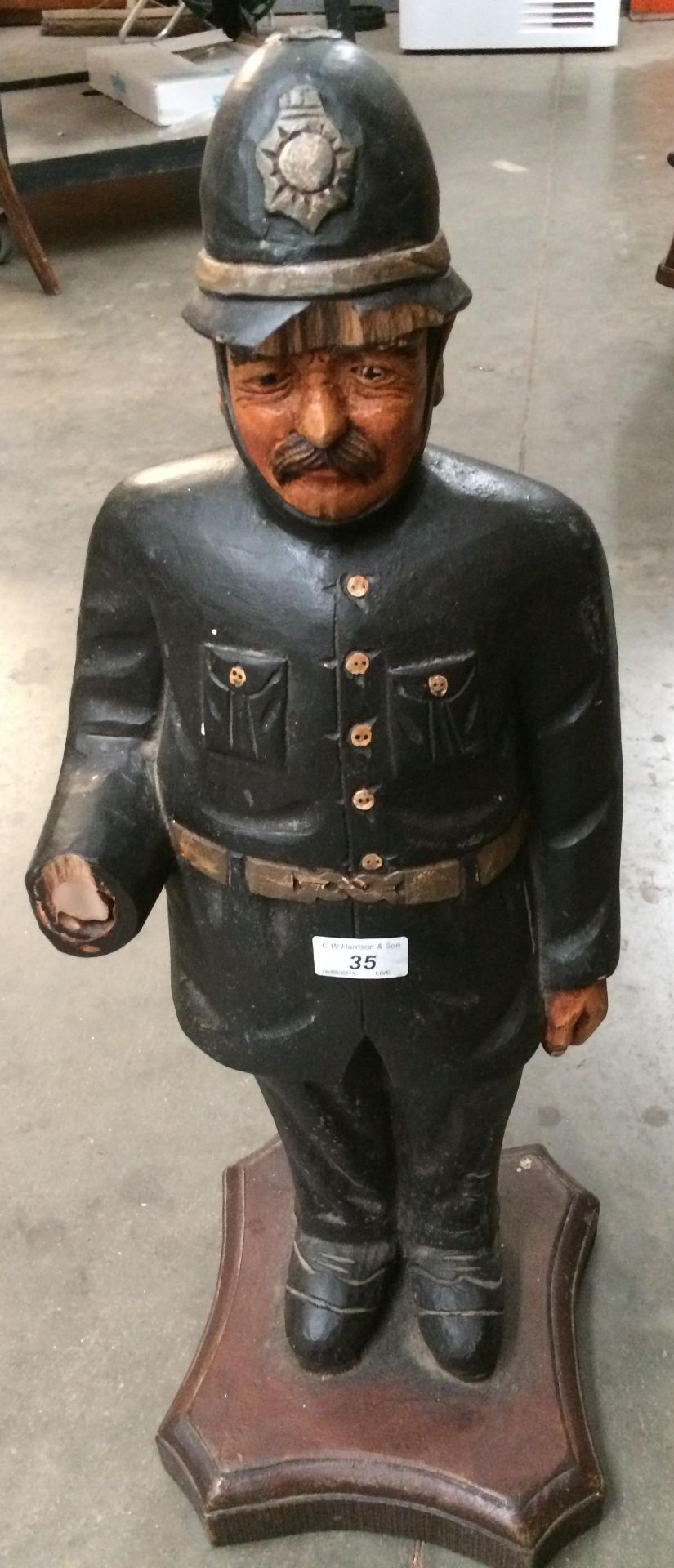 A wooden statue of English police officer 65cm high standing on a wooden plinth (damaged to right