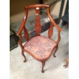 A mahogany framed corner armchair with an orange and grey patterned seat