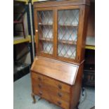 An oak bureau bookcase with upper leaded glazed doors over fall flap three drawer base on cabriole