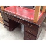 A mahogany 8 drawer (1 mock drawer) reproduction kneehole desk with red leatherette and gilt tooled