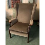 A green dralon upholstered wood trimmed wing back armchair