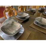 A set of silver coloured bowls with under tray and mats