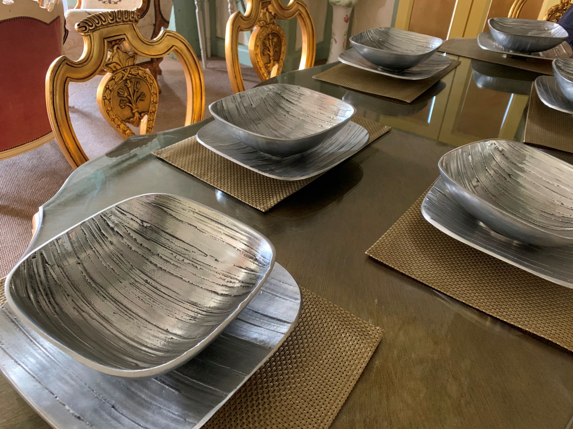 A set of silver coloured bowls with under tray and mats