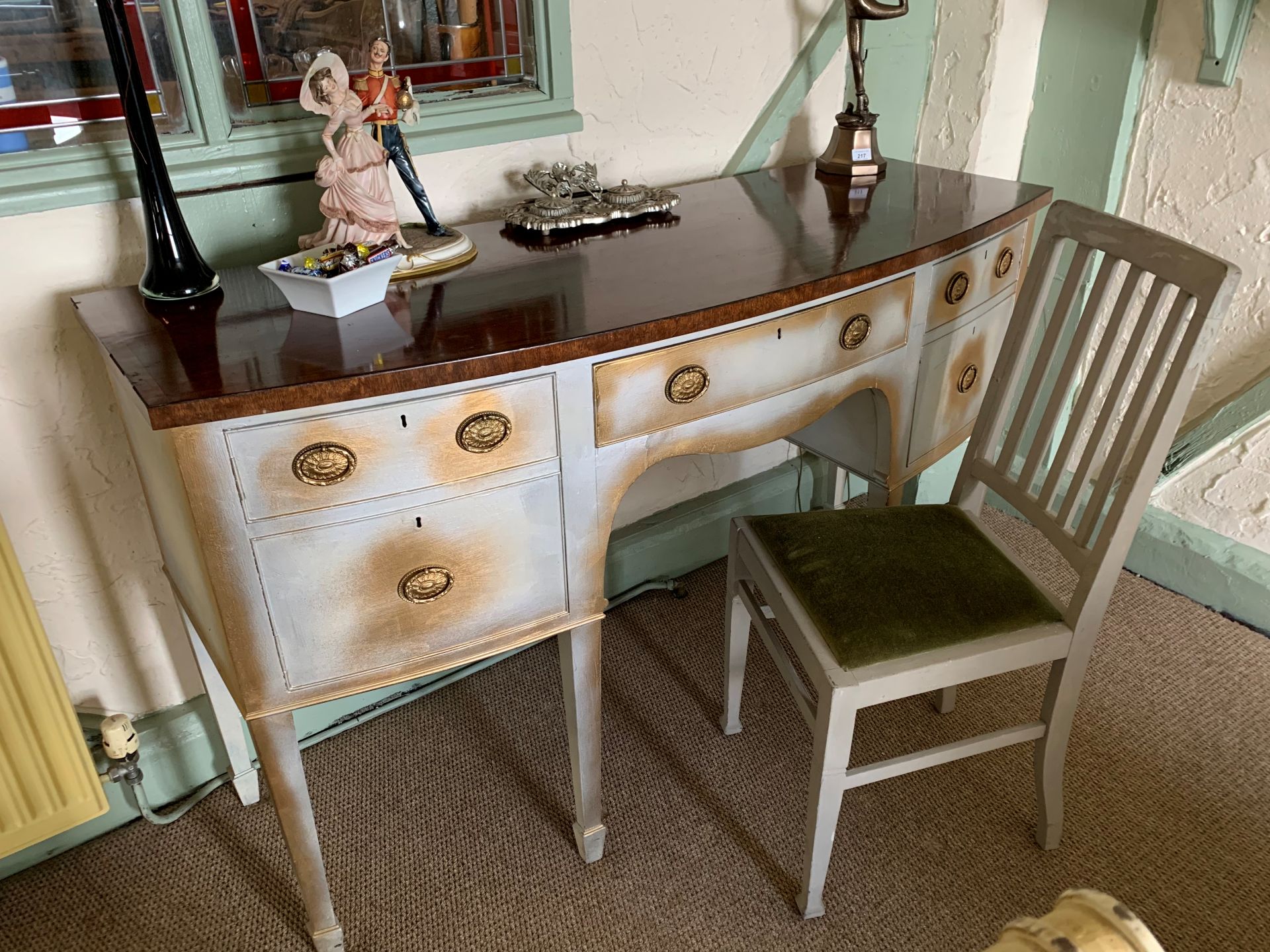 A mahogany topped bow front five drawer sideboard with grey and gilt painted decoration on tapered