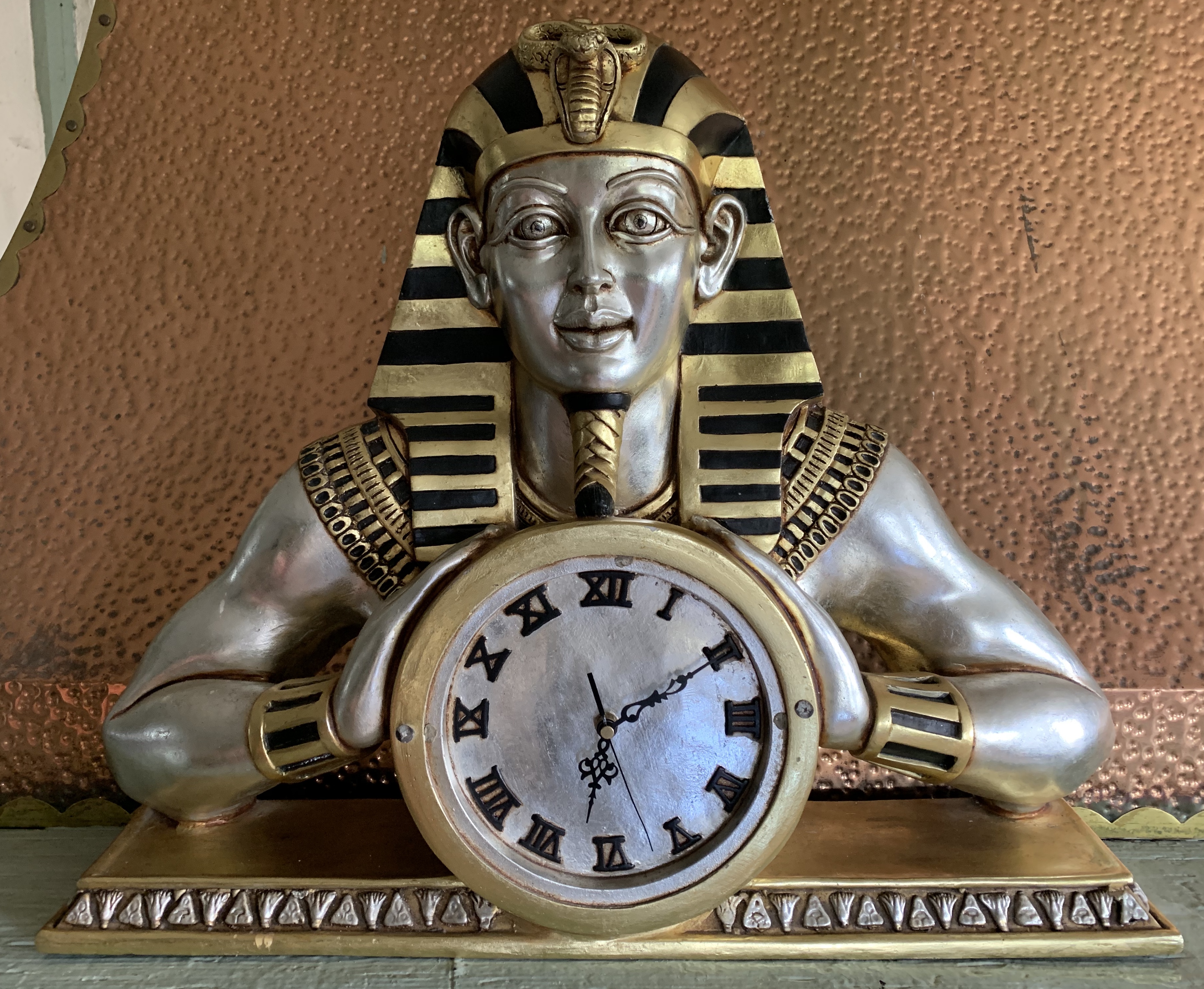 A fibre glass silver and gilt Pharaoh mantel clock 66cm wide