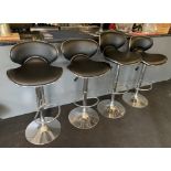 A set of four chrome framed adjustable and swivel bar stools with black vinyl seats and backs