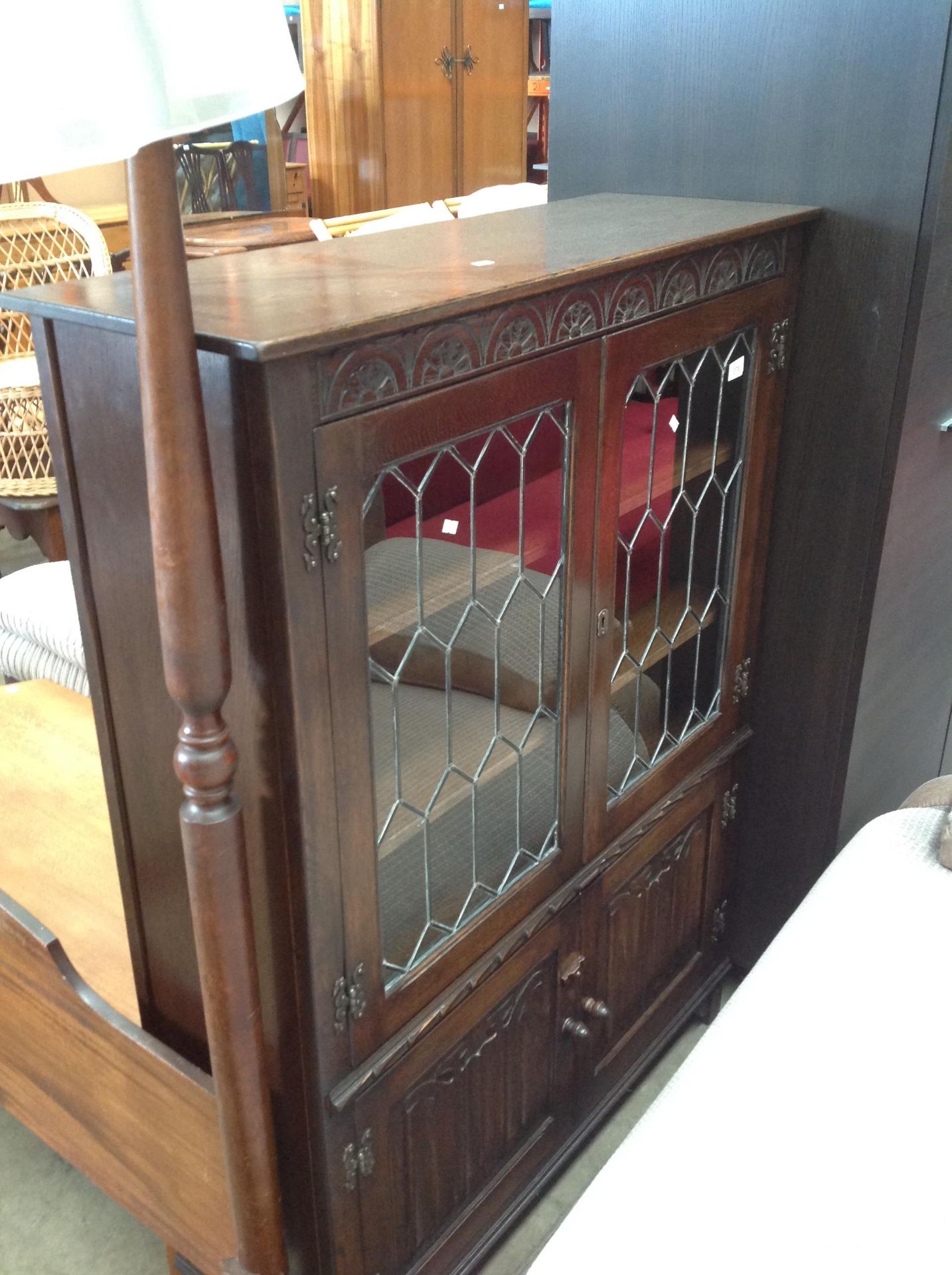 A carved oak bookcase with twin leaded glazed doors over twin linen fold panel doors 95 x 136cm