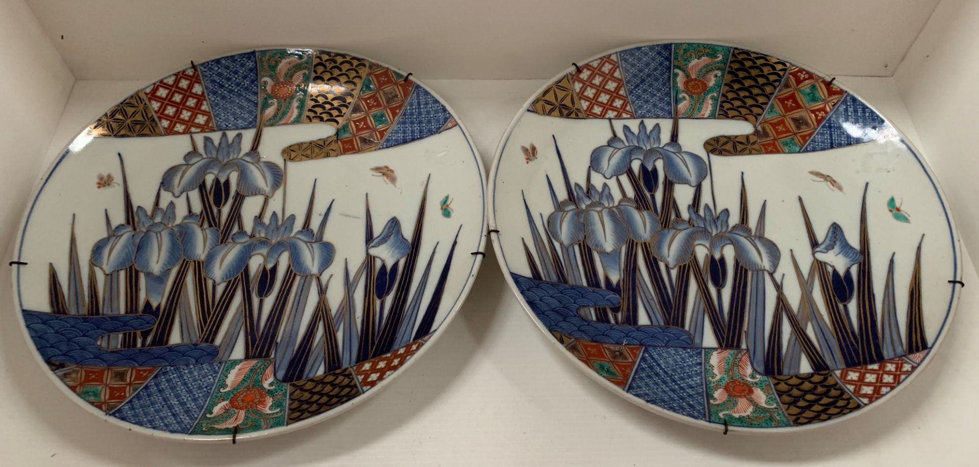 A pair of Japanese Imari porcelain circular wall plates, centrally painted with irises,