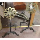 A heavy pair of Arts and Crafts wrought iron and pierced brass floral medallion fire dogs on arched