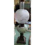 An iron base green glass oil lamp with etched globe