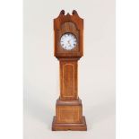 An inlaid mahogany watch stand in the form of a long cased clock containing a silver pocket watch,