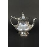 A Victorian silver teapot with ornate floral engraving on flared pedestal base with unusual finial