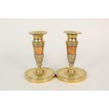 A pair of early 19th Century French brass and copper candlesticks with fluted and chased decoration,