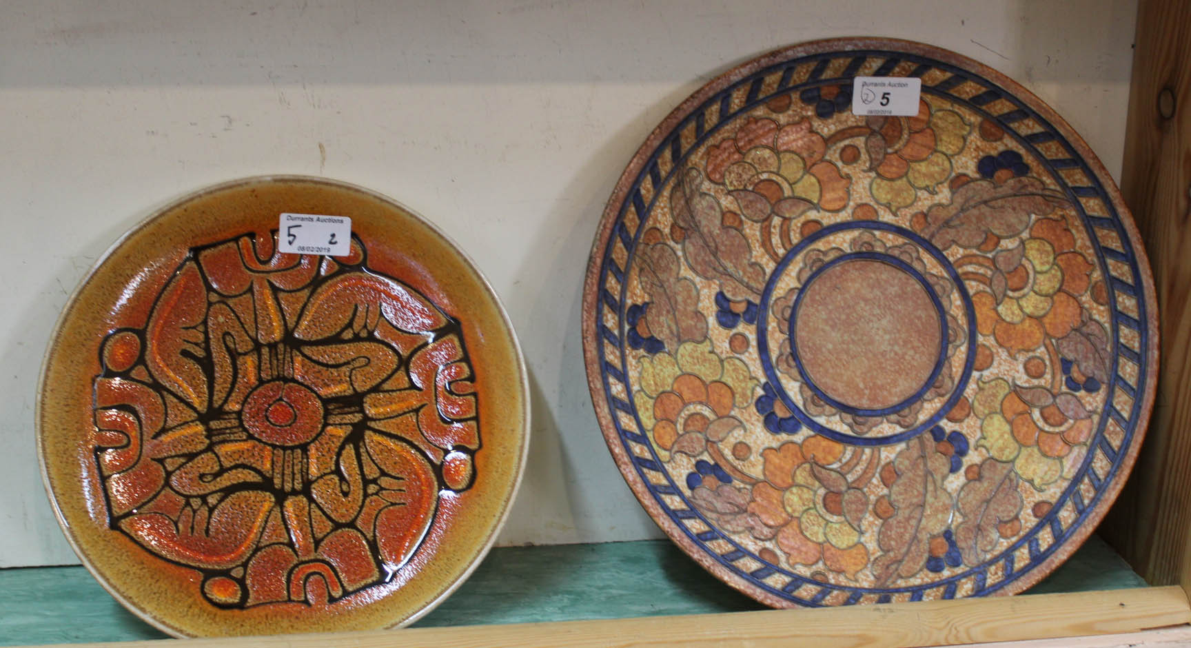 A Charlotte Rhead orange and floral tube lined charger plus a Poole Aegean plate