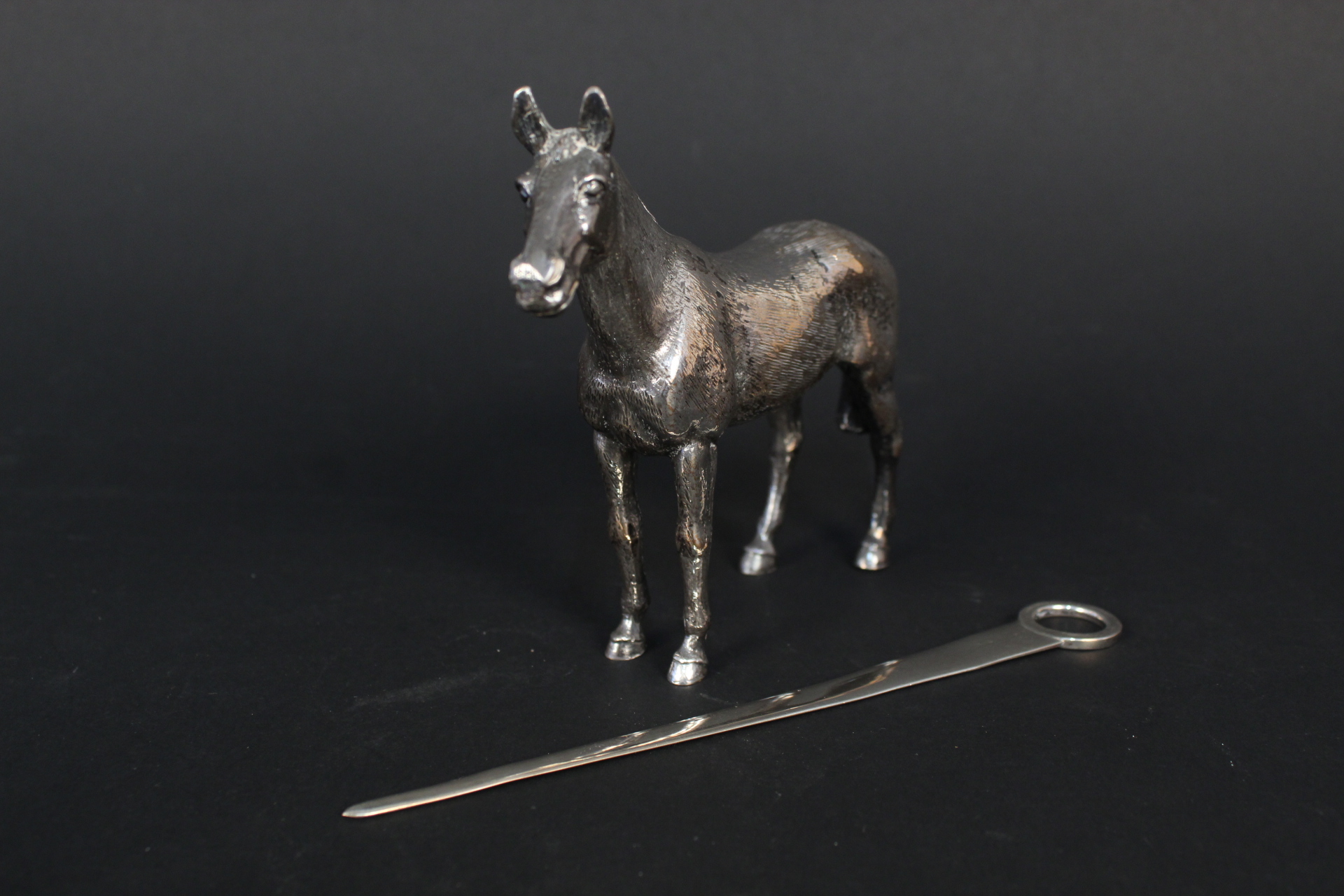 A silver skewer and a large white metal horse ornament