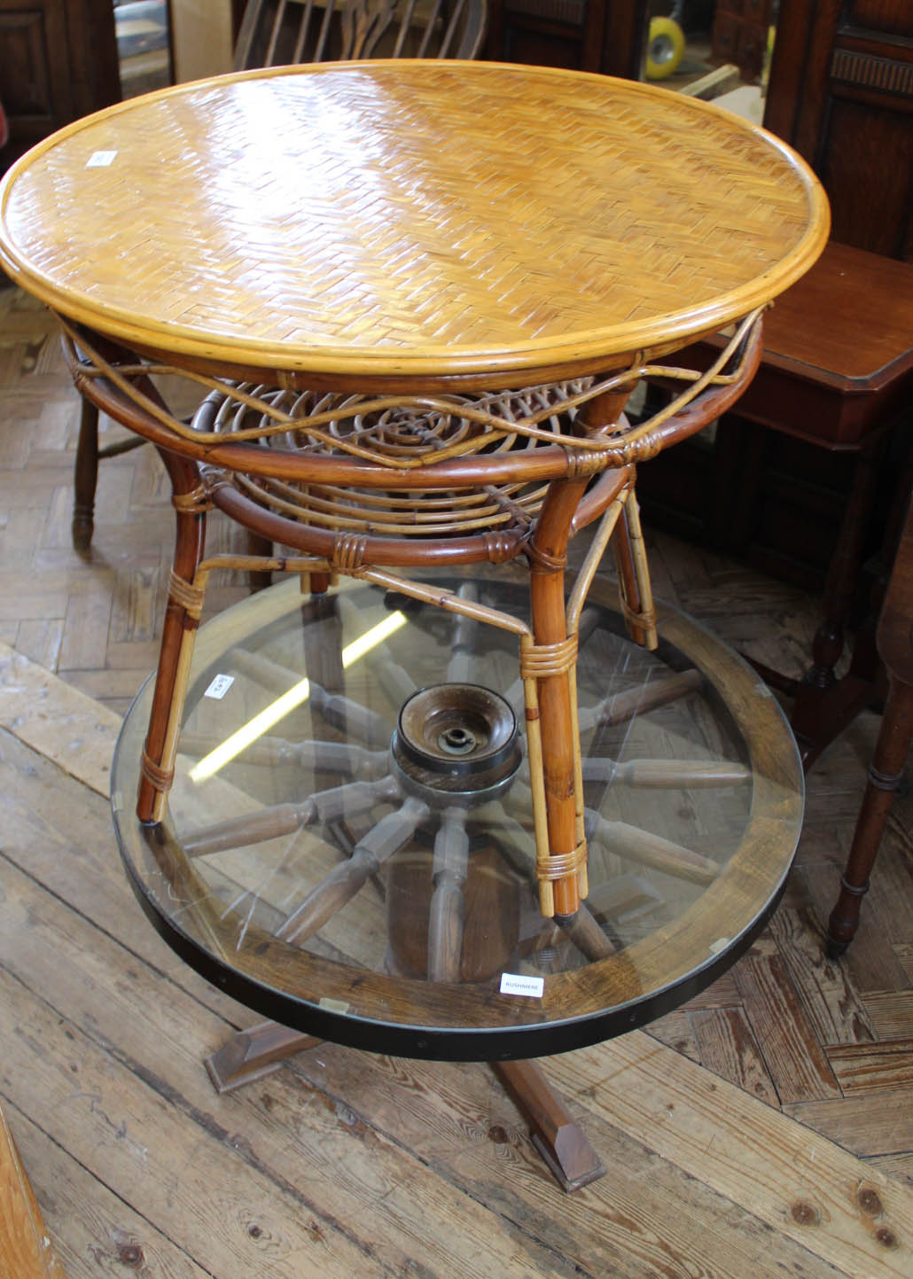 A circular bamboo table and a wagon wheel glass top coffee table