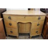 An early 19th Century bow front pine kneehole desk with five drawers on tapered feet