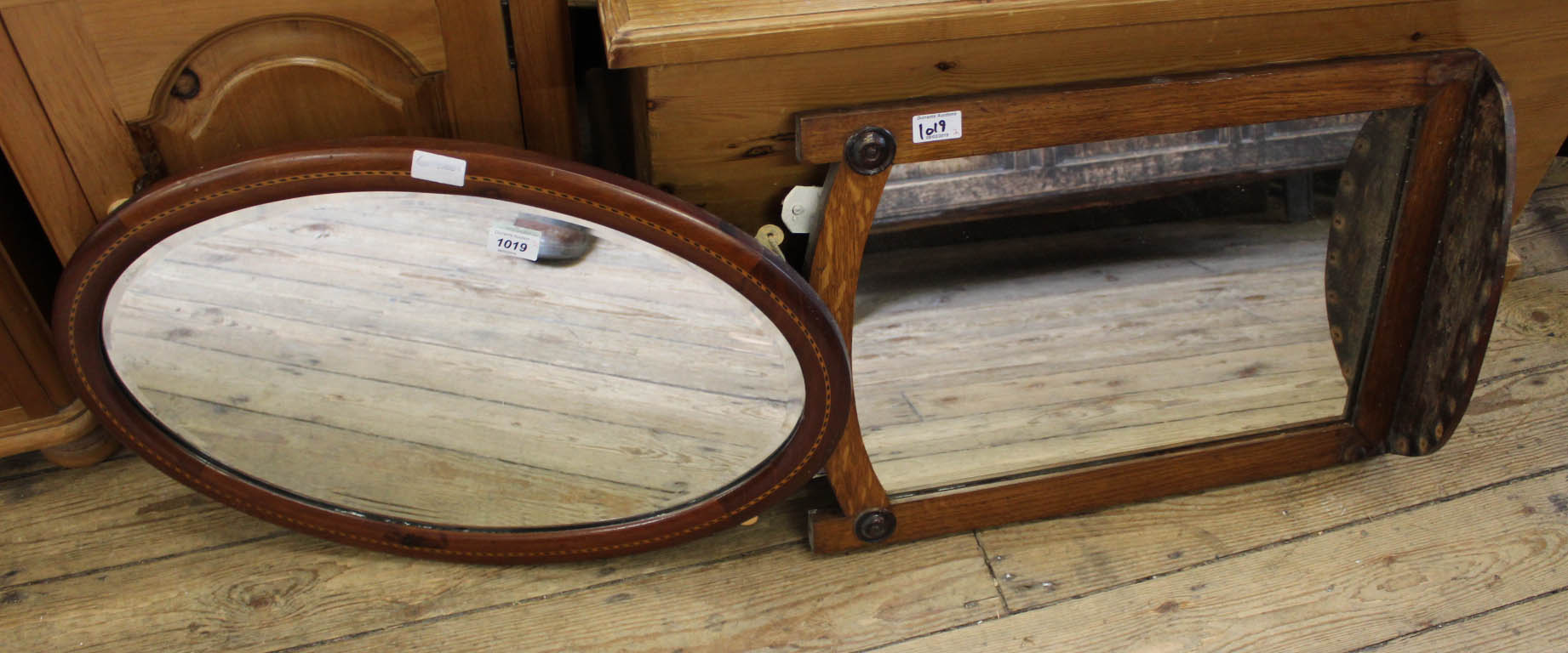 An Edwardian mahogany oval mirror and oak hanging mirror with shelf