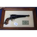 A decorative Remington revolver on framed display,