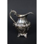 A Victorian silver cream jug with embossed floral decoration on four feet by Richard Pearce &