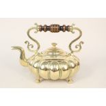 A decorative aesthetic movement brass kettle with gadrooning turned wood handle and four ball feet