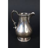 A silver cream jug with ribbed detail to spout and beaded pedestal base,