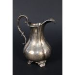 A Victorian silver cream jug with engraved decoration (worn) on four feet (repair to handle) by