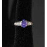 An 18ct white gold oval tanzanite ring with seven baguette cut diamonds either side,