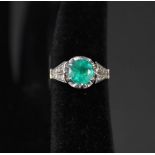 A solitaire emerald set ring with diamond set shoulders set in platinum,