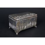 A silver jewellery casket decorated with village scene on body and lid on four paw feel (there are