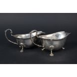 A pair of silver sauce boats on three legs with ribbed border,