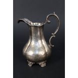 A Victorian silver cream jug with engraved decoration (worn) on four feet (repair to handle) by