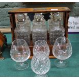 An oak and silver plated three bottle tantalus plus four cut brandy glasses