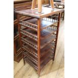 An Edwardian mahogany six tier music stand on brass castors