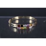 A 9ct gold 'Tutti Frutti' bangle set with multi coloured gemstones