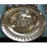 A large 19th Century brass alms dish with central embossed coat of arms and punchwork border,