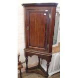 A Georgian oak corner cabinet on stand