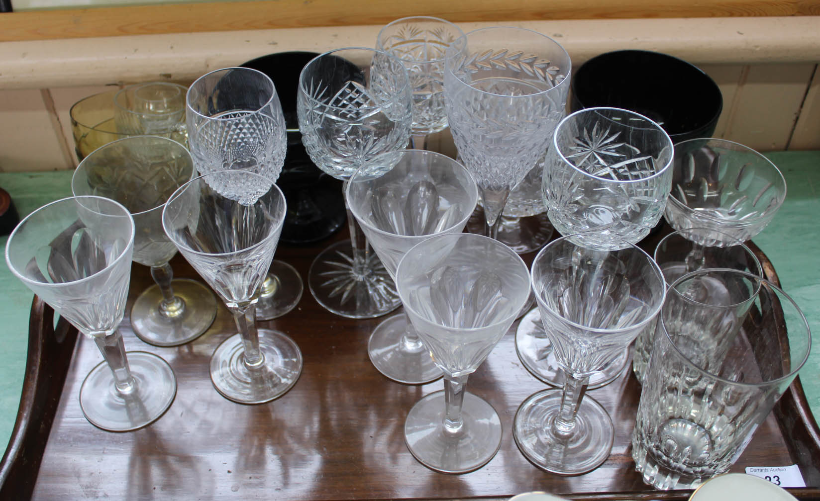 A mahogany tea tray containing slice cut stem plus other wine glasses and two large amber glass