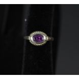 A 9ct gold ring set with oval amethyst in rope border,