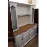 A modern white painted kitchen dresser with glazed and glass shelved top